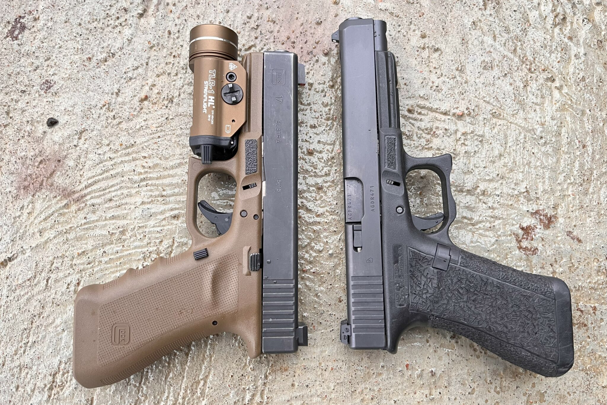 FDE Glock 17 with streamlight TLR-1 weapon light next to a stock Glock 34 all black 
